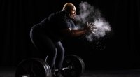 Die schwarze Powerlifterin Tamara Walcott kratzt ihre Hände, bevor sie eine Langhantel macht