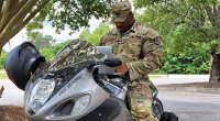 Bodybuilder Cedric McMillan in seiner Armeeuniform auf einem Motorrad