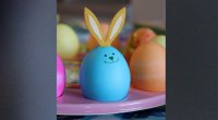 Blaues Osterei mit Hasenohren und einem Smiley-Gesicht