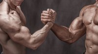 Zwei-muskulöse Männer-Armdrücken-Hände halten