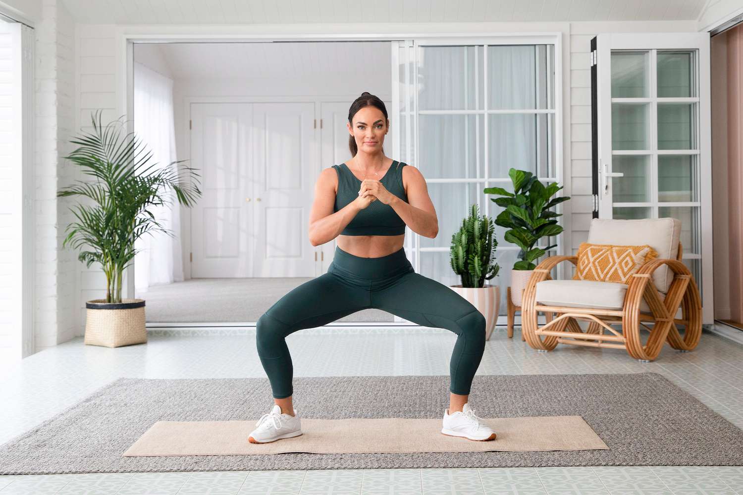 Frau im grünen Trainingsset, das eine Sumo-Kniebeuge macht