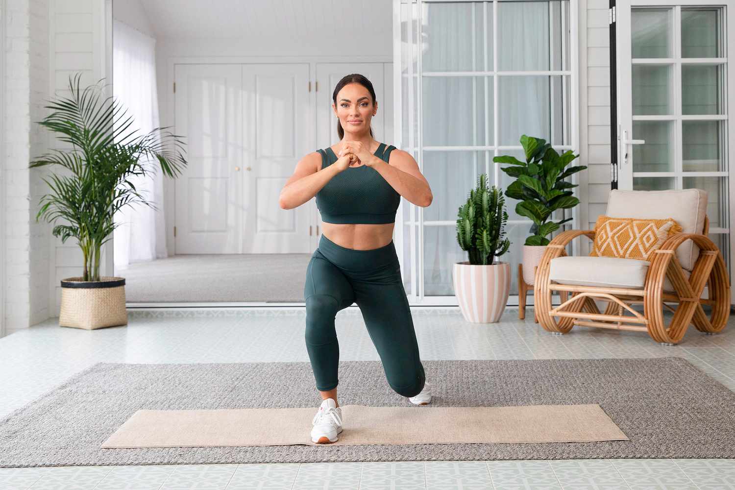 Frau im grünen Trainingsset macht einen Ausfallschritt